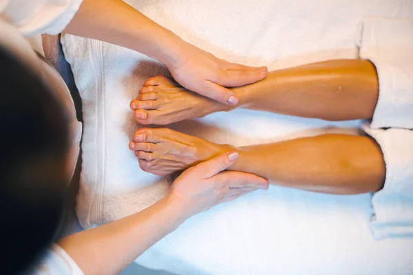 Visão superior de mãos de massagistas que dão a massagem de óleo essencial a umas pernas de mulher no salão de spa. Fecha o retrato. Spa cuidados com o corpo. Cuidados com a pele beleza. — Fotografia de Stock