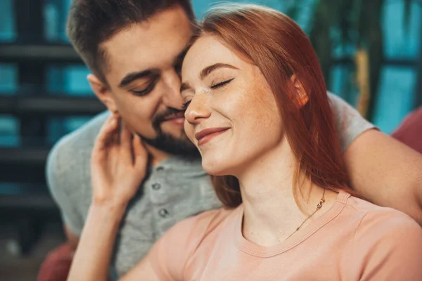 Närbild porträtt av två personer i kärlek leende med slutna ögon sitter på soffan. Närbild porträtt. Hemma koncept. Lyckliga människor. Njuta av livet koncept. — Stockfoto