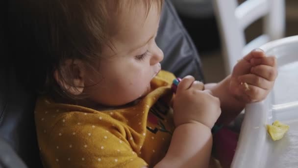 Video met moeders handen voeden baby meisje met een speeltje in haar handen. Babyverzorging. — Stockvideo