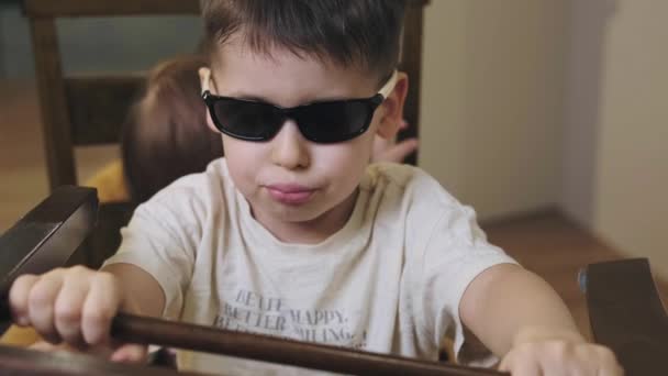 Vidéo frère aîné portant des lunettes avec la petite sœur jouant semblant d'aller à la voiture. Frères jouant imiter la voiture dans un style fantastique. Concept de garde d'enfants — Video