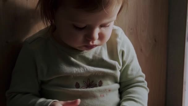 Video with a baby girl sitting in the kitchen eagerly eating an orange. Vegetarian healthy food. Organic food. Holding hand. — Stok video