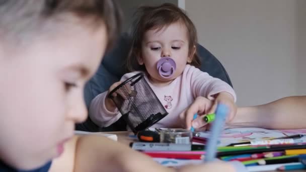 Lillasyster leker med sina bröder pennor medan han gör sina läxor. Utbildning för barn. Distansutbildning. Video — Stockvideo