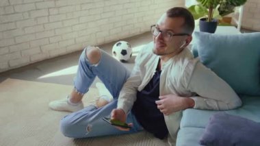 Oturma odasında kanepede yatarken smatphone ve tablet kullanan bir adamın videosu. mobil iletişim. Cep telefonu. İş iletişimi.