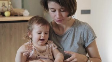 Anne bir bebeği elinde tutuyor ve kızlarının ellerine antibakteriyel sprey sıkıyor. Aile bakımı. Aile koruması. Bebek bakımı.