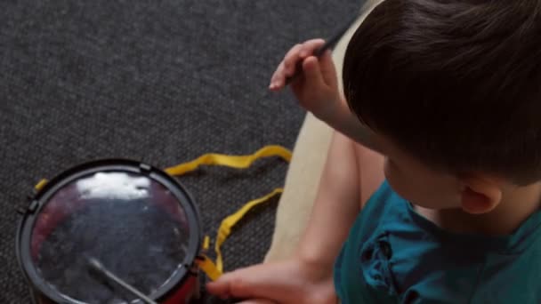 Kaukasisch jongetje aan het drummen op de vloer. Ontwikkeling van het kind — Stockvideo