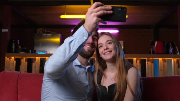 Vídeo de um casal caucasiano tirando fotos com eles para lembrar seu primeiro encontro. Boas festas. Cidade nocturna. Férias. — Vídeo de Stock