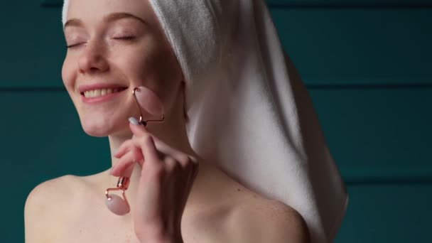 Video de una mujer caucásica desnudo alf pecosa masajeando la cara con rodillo de jade. Procedimiento de belleza de cosmetología. Hermosa chica. — Vídeos de Stock