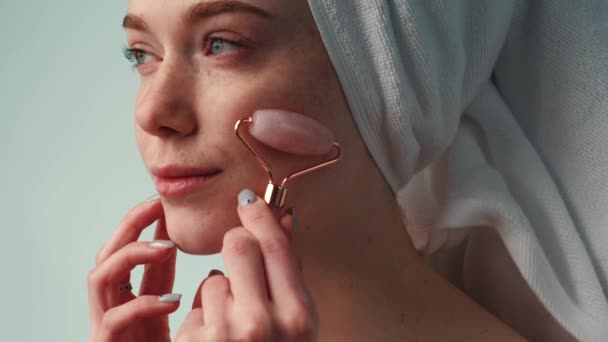 Wideo z portretem kobiety używającej jadeitowego wałka do masażu twarzy na białym tle.Pielęgnacja skóry piękna. Skóra piękna kobieca. Szczęśliwy. — Wideo stockowe