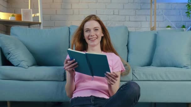 Відео жінки, яка сидить на підлозі і думає про наступні плани, які вона повинна зробити, щоб писати свої ідеї в щоденнику — стокове відео