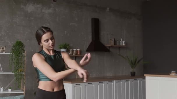 Βίντεο μιας καυκάσιας γυναίκας που στέκεται στην κουζίνα και απλώνει τα χέρια της στο σπίτι. Υγιεινός τρόπος ζωής. Αθλήματα, υγιεινός τρόπος ζωής. Εκτεινόμενη δραστηριότητα. Υγεία — Αρχείο Βίντεο
