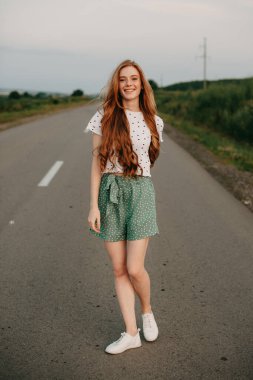 Kızıl saçlı kadın boş yolda yürüyor. Moda modeli.