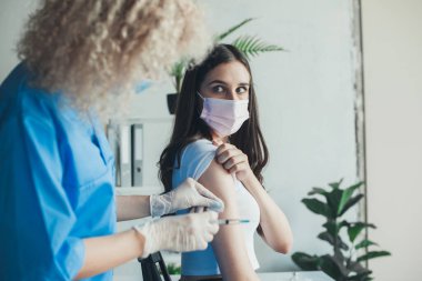 Doktor, aşıyı uygulamadan önce kadın kolunu temizlemek için alkollü pamuk çubuğu kullanıyor. Coronavirus aşısı. Virüs koruması. Doktor eli..