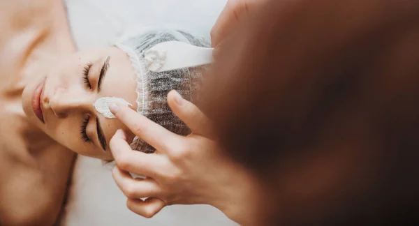 Toepassing van cosmetologie masker op het gezicht van een vrouw in spa salon. Gezichtsbehandeling. Schoonheidsverzorging. — Stockfoto