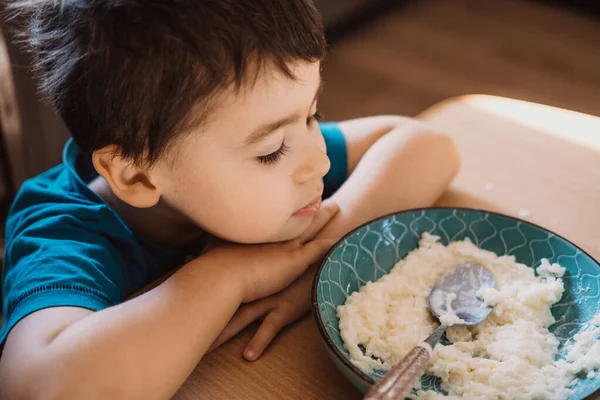 Мальчик, сидящий за столом, не хочет есть в детском саду. Мальчик не хочет завтракать. Здоровое питание. — стоковое фото