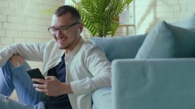 Adam, iş arkadaşlarıyla telefonda konuşurken koltuğa yaslanmış bir şekilde oturuyor. Çevrimiçi iletişim. Çevrimiçi bağlantı.