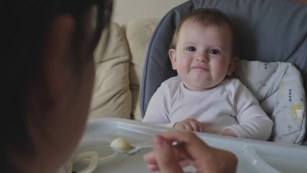Vídeo con las manos de las madres alimentando al bebé con una cuchara, dándole comida saludable. Cuidado familiar. Cuidado del bebé. — Vídeos de Stock