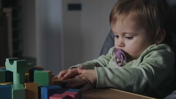 Video met een baby meisje zitten aan de tafel in de babykamer spelen met kleuren educatief speelgoed. Voor spelontwerp. — Stockvideo