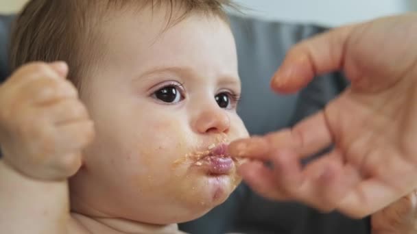 Video con le mani delle mamme che danno cibo omogeneizzato a sua figlia. Bambina che copre il suo viso con le mani e accigliato — Video Stock