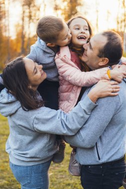 Parkta poz veren dört kişilik mutlu bir aile. Yakından bir portre. Birlikte vakit geçirmek..