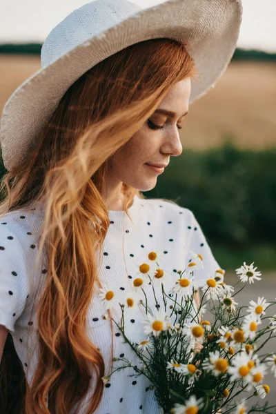 Biała kobieta w kapeluszu trzymająca bukiet stokrotek. Portret z bliska. Naturalne piękno. Piękna dziewczyna. Wiosenny bukiet. Pole kwiatów rumianku. Piękna twarz. Wiosna — Zdjęcie stockowe