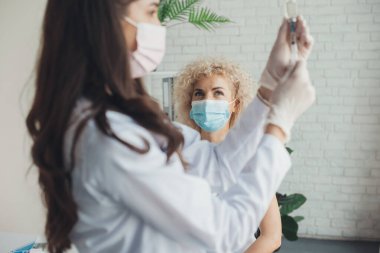 Tıbbi maske takan beyaz bir hasta aşıyı hazırlarken aşı olmak için bekliyor. Corona virüsünün önlenmesi. Coronavirüs