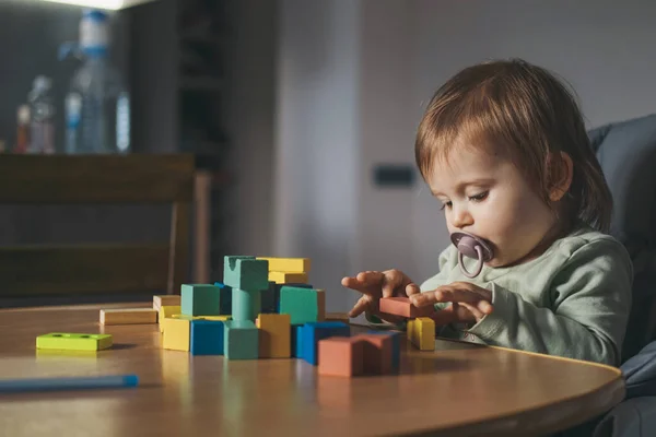 Menina brincando com blocos de madeira sentados em casa. Jogando construção. — Fotografia de Stock