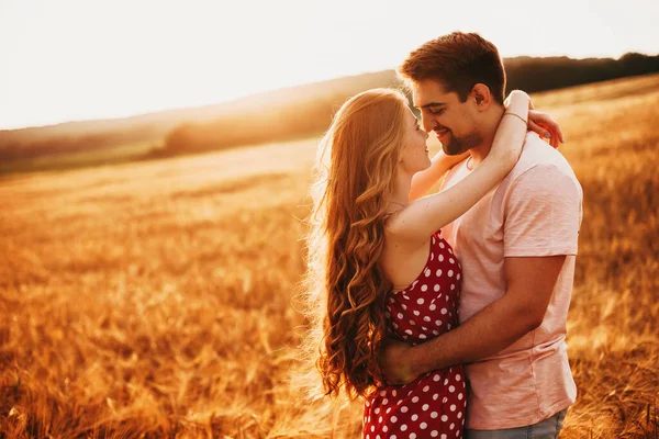 Un hombre y una mujer abrazándose contra el fondo del sol poniente en un campo de trigo. Naturaleza paisaje. Campo de trigo. —  Fotos de Stock