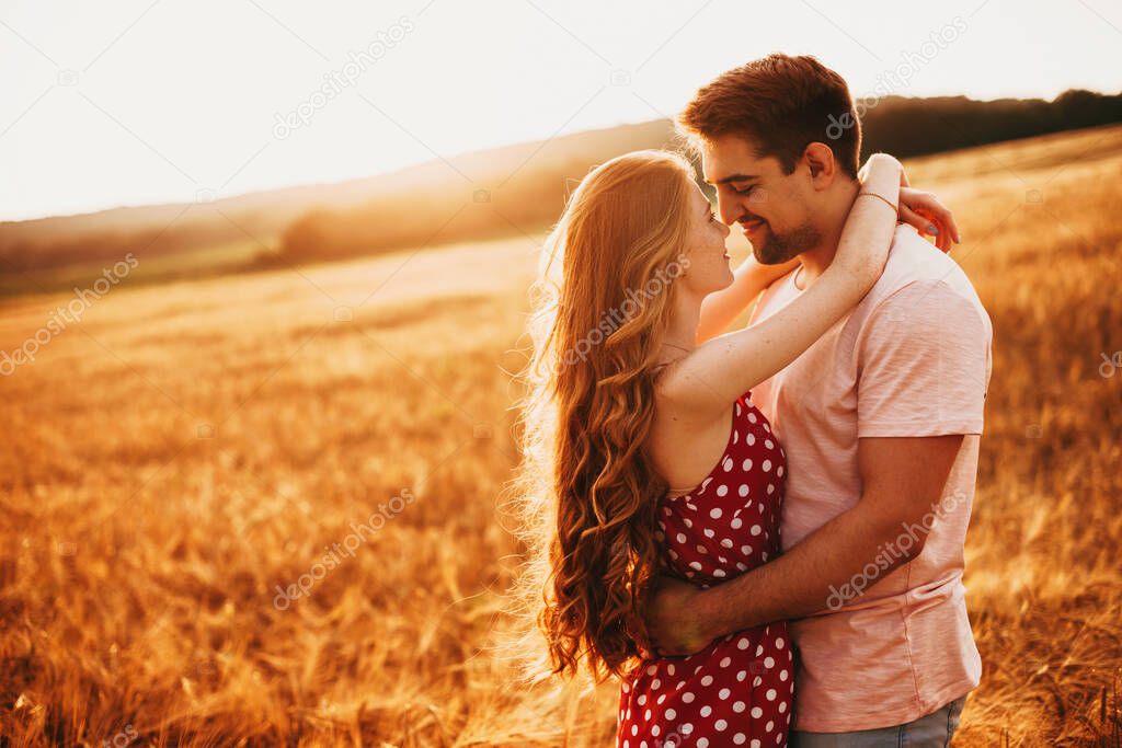 A man and a woman embracing against the background of the setting sun in a wheat field. Nature landscape. Wheat field.