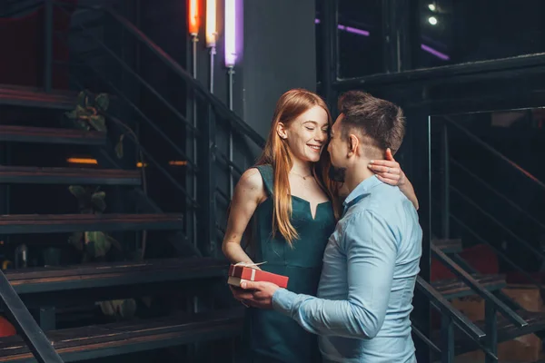 이 남자는 결혼 2 년만에 빨간 머리의 여자 친구를 놀래키며 레스토랑 데이트 때그녀에게 선물을 주었다. 주는 일이라는 개념 — 스톡 사진
