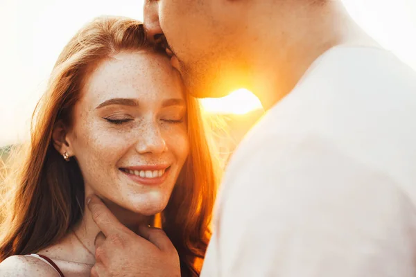 Donna spericolata sorridente mentre viene baciata sulla fronte dalle labbra dei suoi fidanzati. Bella coppia che si abbraccia in un viaggio su strada, grande design per qualsiasi scopo. — Foto Stock