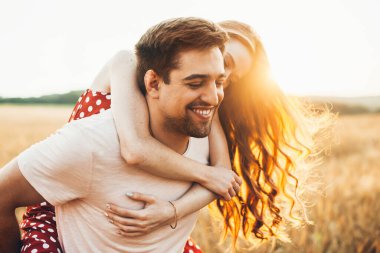 Yakın plan bir portre. Açık alanda oynayan bir çift erkek ve kadın. Sırt sırta biniyorlar..