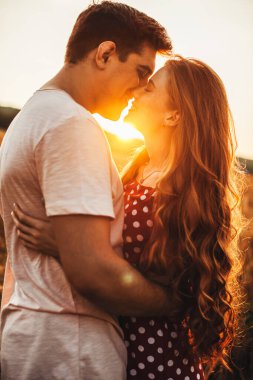 Kafkasyalı bir çiftin öpüşmeden önce birbirlerine sarılıp flört etmesi. Işık arka planı. Yaz tatili. Yakın plan portre.
