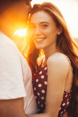 Bir unui cuplu, lanul de grau 'da imbratisat, fata pistruiata a femeii uitand use si zambind la camera. Doğa manzarası.