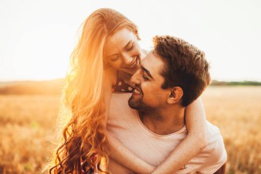 Kocasının arkasında çilli yüzlü kızıl saçlı bir kızın yakın plan portresi. Gün ışığında boynuna sarılıyor. Yaşam tarzı tasarımı için. Sağlıklı