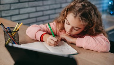 Liseli kız ödevini evde dijital tabletle yapıyor. Uzaktan eğitim. İnternette okuyan bir kız. Modern online eğitim.