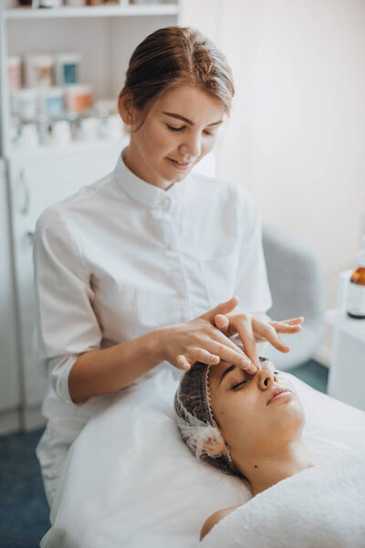 Close up portrait of caucasian masseuse hands massaging client face in the spa salon. Health care. Body care.