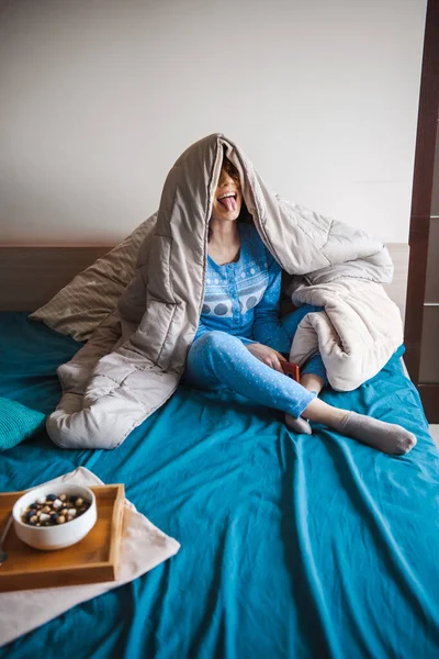 Γυναίκα καλύπτει το κεφάλι της με μια κουβέρτα κάθεται στο κρεβάτι, ενώ γκρίνια. Πρωινή ώρα. Υγιεινή διατροφή. — Φωτογραφία Αρχείου