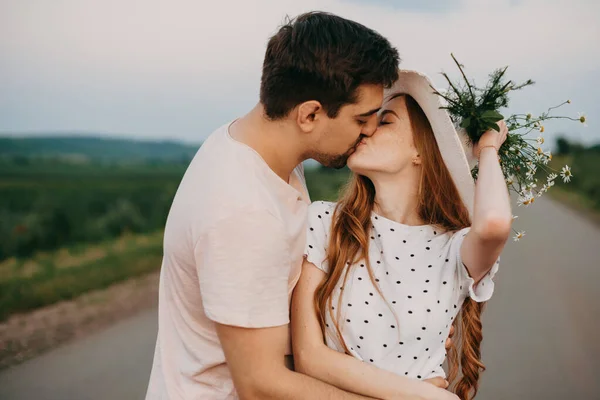 Портрет влюблённой пары, целующейся и обнимающейся посреди проселочной дороги. Прекрасный летний пейзаж. Летние каникулы. Красивая девушка. — стоковое фото