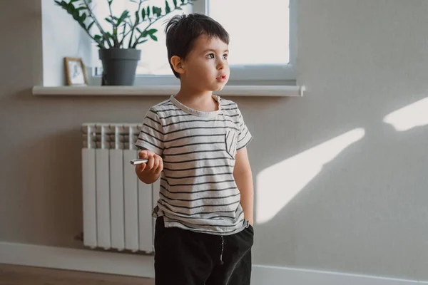 O menino está de pé na casa olhando através das partes onde seus pais estão. Retrato vertical. Garoto caucasiano. — Fotografia de Stock