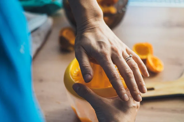 Gros portrait de femmes mains serrant le jus de l'orange mûre dans la cuisine. Aliments frais et sains. Mode de vie sain. Nutrition biologique naturelle. — Photo