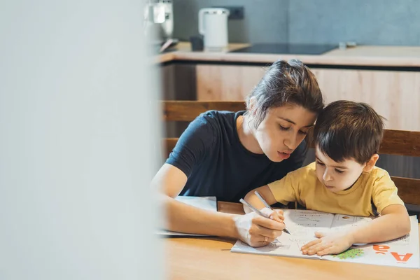 Mãe ajudando filho fazendo lição de casa em casa. Pais a ajudar a criança. Rapaz da escola. — Fotografia de Stock