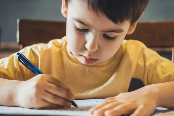 Close-up portret van een hardwerkende jongen die huiswerk maakt tijdens quarantainetijd. Thuisonderwijs concept. Studeren, huiswerk maken. — Stockfoto