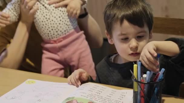 Küçük okul çocuğu masa başında okuyor, yazıyor ve öğreniyor. Mutlu aile birlikte. Aile hobisi. — Stok video