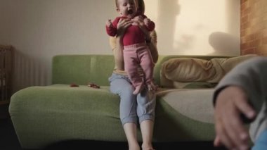 Anne öğleden sonra çocuklarıyla oynuyor kanepede oturuyor ve ayaklarına tutunuyor. Gülümseyen mutlu çocuk. Sağlıklı bir yaşam tarzı. Aile bakımı. Bebeğim.