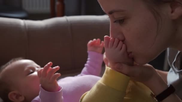 母親は赤ん坊の足をベッドに寝そべってキスをする 家族の保護 スキンケア ベビーケア — ストック動画