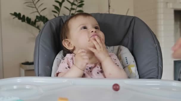 赤ん坊のテーブルの上にベリーを投げる人間の手 彼は取り 彼の口の中に置きます おいしい料理 — ストック動画