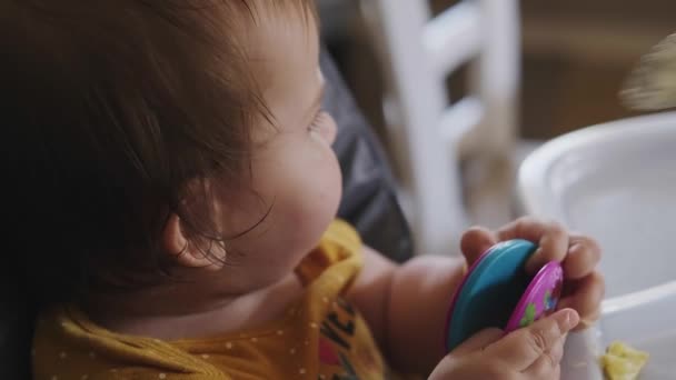 婴儿坐在婴儿桌旁玩玩具 而他的母亲用勺子喂他 家庭护理 幼儿保育 — 图库视频影像