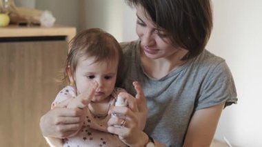 Anne ve bebek ellerini dezenfektanla dezenfekte ediyor. Karantinada birlikte oturuyorlar. Sağlık hizmeti konsepti. Coronavirus önleme. Aile bakımı.