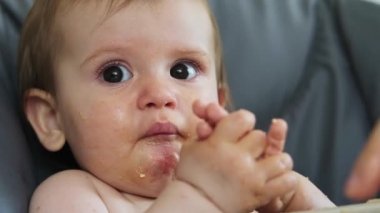 Sağlıklı bir yemekten sonra kirli elleriyle oynayan bir bebeğin portresi. Yüzüne sürüp her tarafını kirletiyor. Sağlıklı yiyecekler. Aile bakımı. Bebeğim.