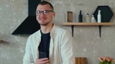 Elinde telefon tutan ve kameraya bakarken komik bir hikaye anlatan bir adamın portresi. Yaşam tarzı tasarımı için portre. Mobil iletişim. Cep telefonu çağrısı.